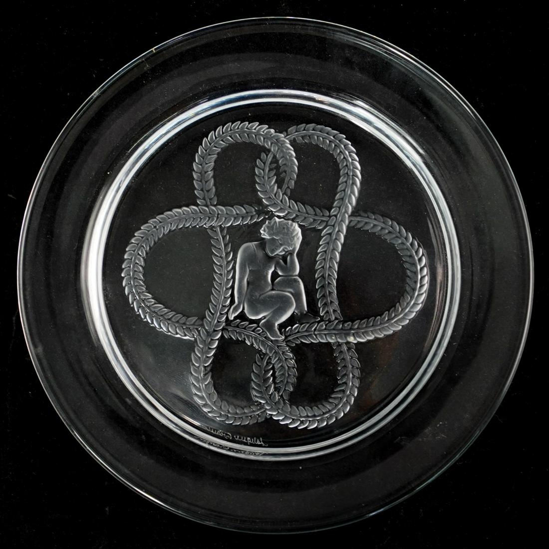 Lalique Olympe Crystal Plates: DESCRIPTION: A Lalique France intaglio crystal plate, in the "Olympe" pattern. Depicting a cherub in interwoven leaf garland. Marked: "Lalique France" CIRCA: 20th Century ORIGIN: France DIMENSIONS: D.