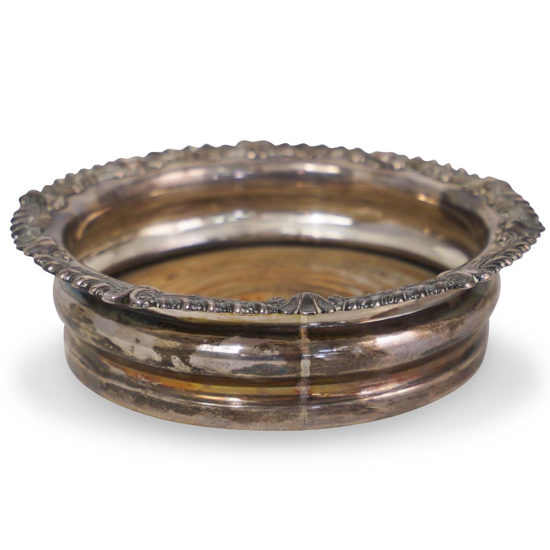 Sheffield Silver Plated Wine Coaster: DESCRIPTION: A Sheffield silver plated wine bottle coaster with repousse design border. Hallmarked along the base. CIRCA: 20th Century ORIGIN: England DIMENSIONS: H. 1.75" x D. 6.5" CONDITION: Great c