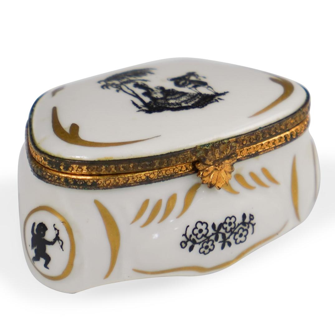 Singer Limoges Porcelain Dresser Box: DESCRIPTION: A Singer Limoges porcelain dresser box. Features a Victorian motif with gilded trims. Finished with a gilt metal lining and a floral motif clasp. Marked along the underside: "singer Limog