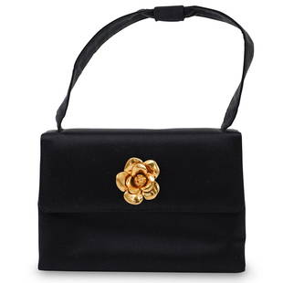 Chanel Vintage Black Satin Handbag: DESCRIPTION: A Vintage Chanel black satin evening handle bag with gold camellia flower detail. Labeled "Chanel" Includes dust bag.CIRCA: 1990sORIGIN: ItalyDIMENSIONS: H. 10" x W. 7"CONDITION:
