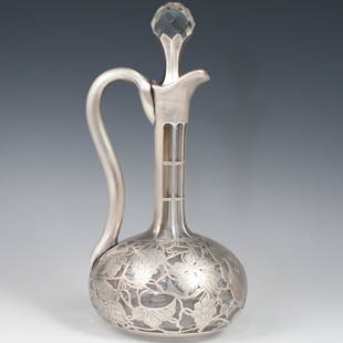 Sterling Silver Overlay Decanter: DESCRIPTION: Sterling Silver Overlay Decanter. Intricate grape and vine design throughout. Flanked by a curving sterling silver handle connecting the top and bottom. Stamped "Sterling", "D 219" CIRCA: