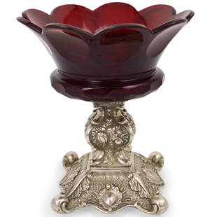 Continental Sterling and Crystal Compote: DESCRIPTION: A Continental compote features a sterling silver base decorated with repousse designs of floral bouquets and lead wreaths, fitted at the top with a crystal cut cranberry bowl. CIRCA: Earl