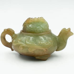 Antique Chinese Jade Teapot: DESCRIPTION: An antique Chinese hand carved footed teapot in a multi green color. The carving features a dragging on each side, one on the lid and the handle.CIRCA: 18/19th ctORIGIN: ChinaDIMENSIONS:
