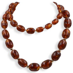 Amber Beaded Necklace: DESCRIPTION: A hand knotted amber beaded necklace featuring gold spacers along the bottom beads.CIRCA: 20th Cent.DIMENSIONS: L: 17" ClosedCONDITION: Great condition. See lot description for details