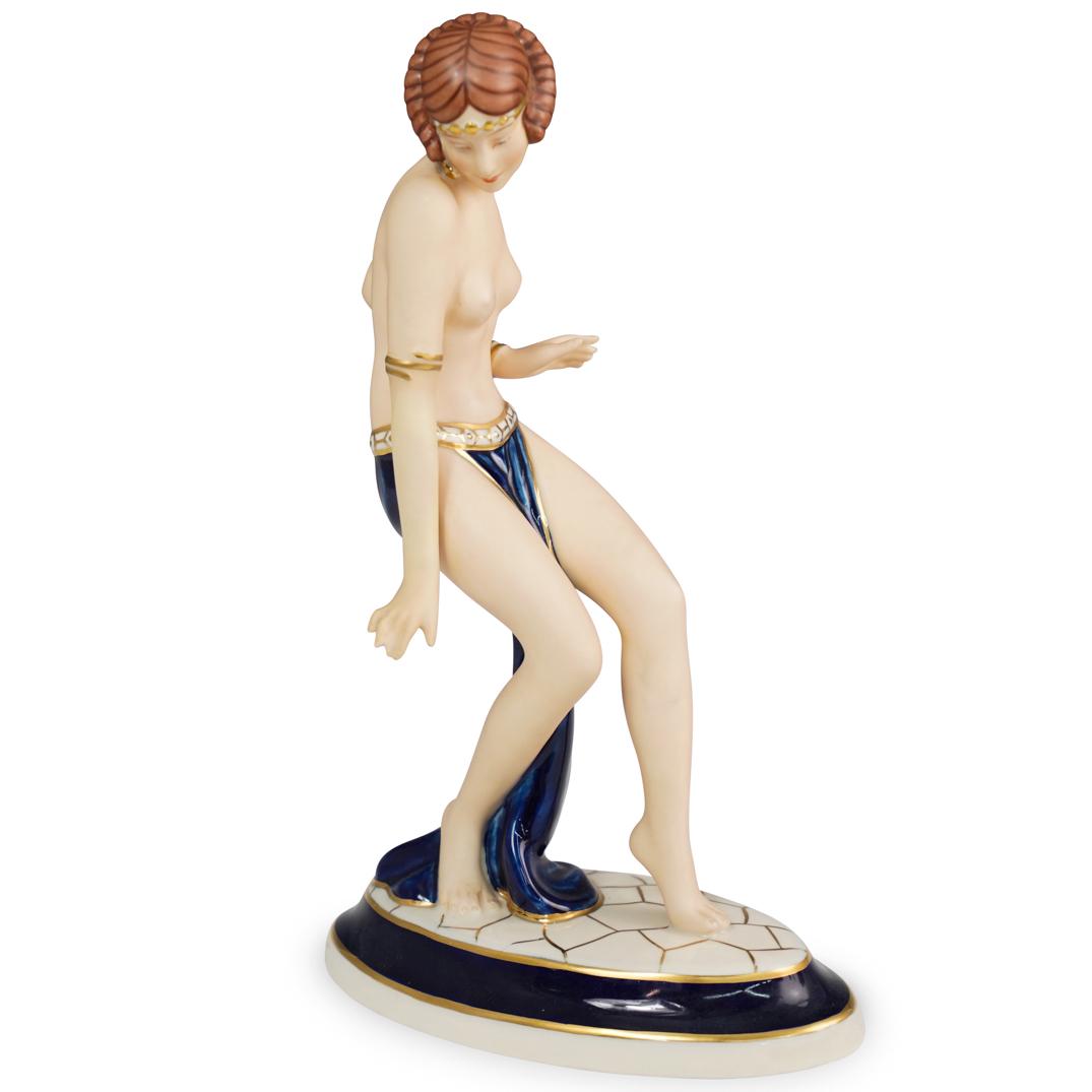 Royal Dux Art Deco Figurine: DESCRIPTION: A Royal Dux porcelain figurine. Depicting a semi-nude dancer in a cobalt skirt with gilded borders. Stamped on the underside. CIRCA: Early 20th Century ORIGIN: Czechoslovakia DIMENSIONS: 