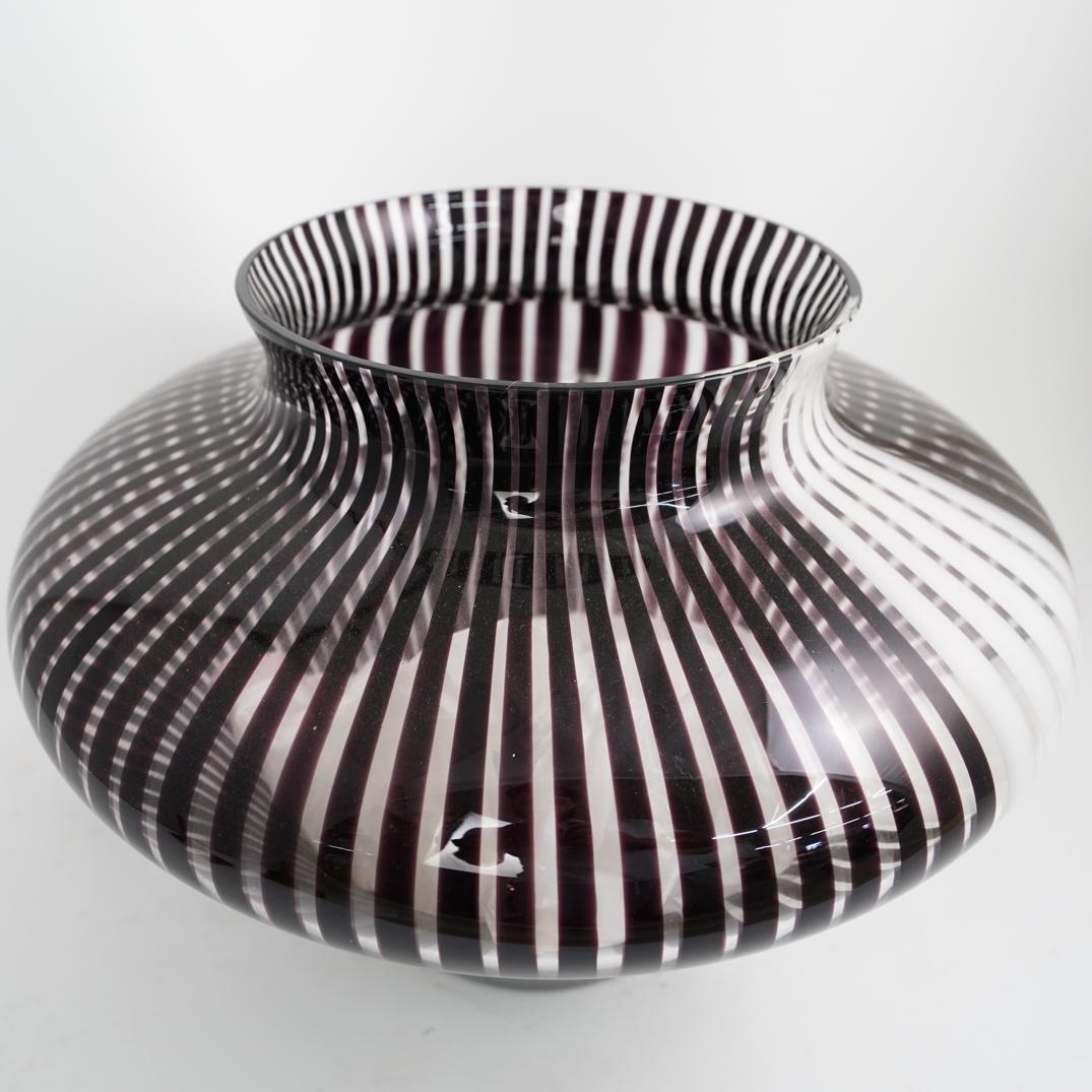 Murano Glass Vase: DESCRIPTION: An Italian murano art glass vase featuring a clear glass foundation with purple and white vertical stripe formations. Labeled on the underside, "Made in Italy" CIRCA: 20th Century ORIGIN: