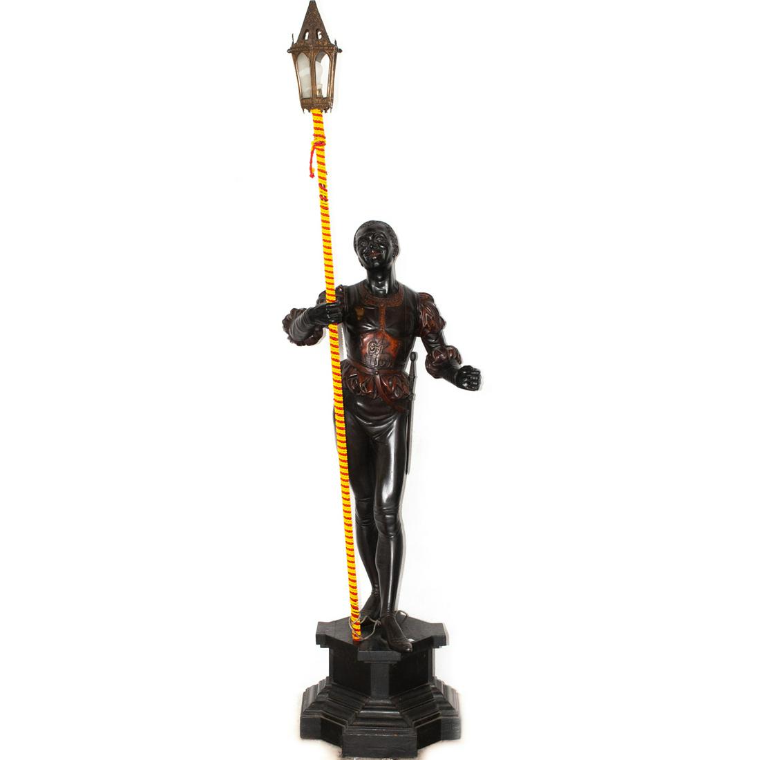 Signed Italian Wooden Blackamoor Lamp: DESCRIPTION: Italian Wooden Blackamoor Statue on Wooden Base. The figure is in a stance, holding a spear with a lantern affixed to the top. Signed on the base indistinctly with artist name, additional