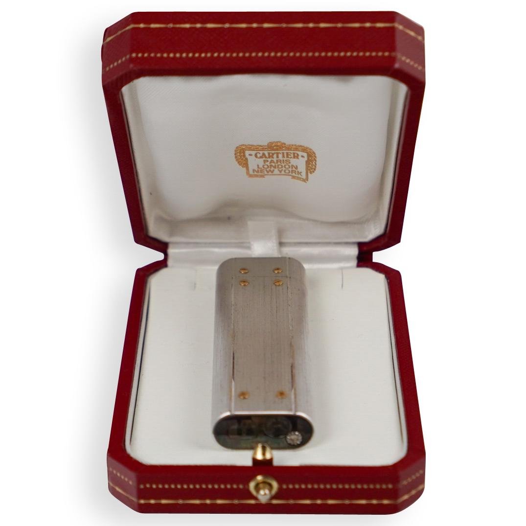 Cartier Santos Stainless Steel Lighter: DESCRIPTION: A Cartier "Santos" lighter composed of stainless steel with 18k gold screw accents. In working condition needs lighter fluid, marked along the bottom "Cartier Paris" with S# 92246V. With 