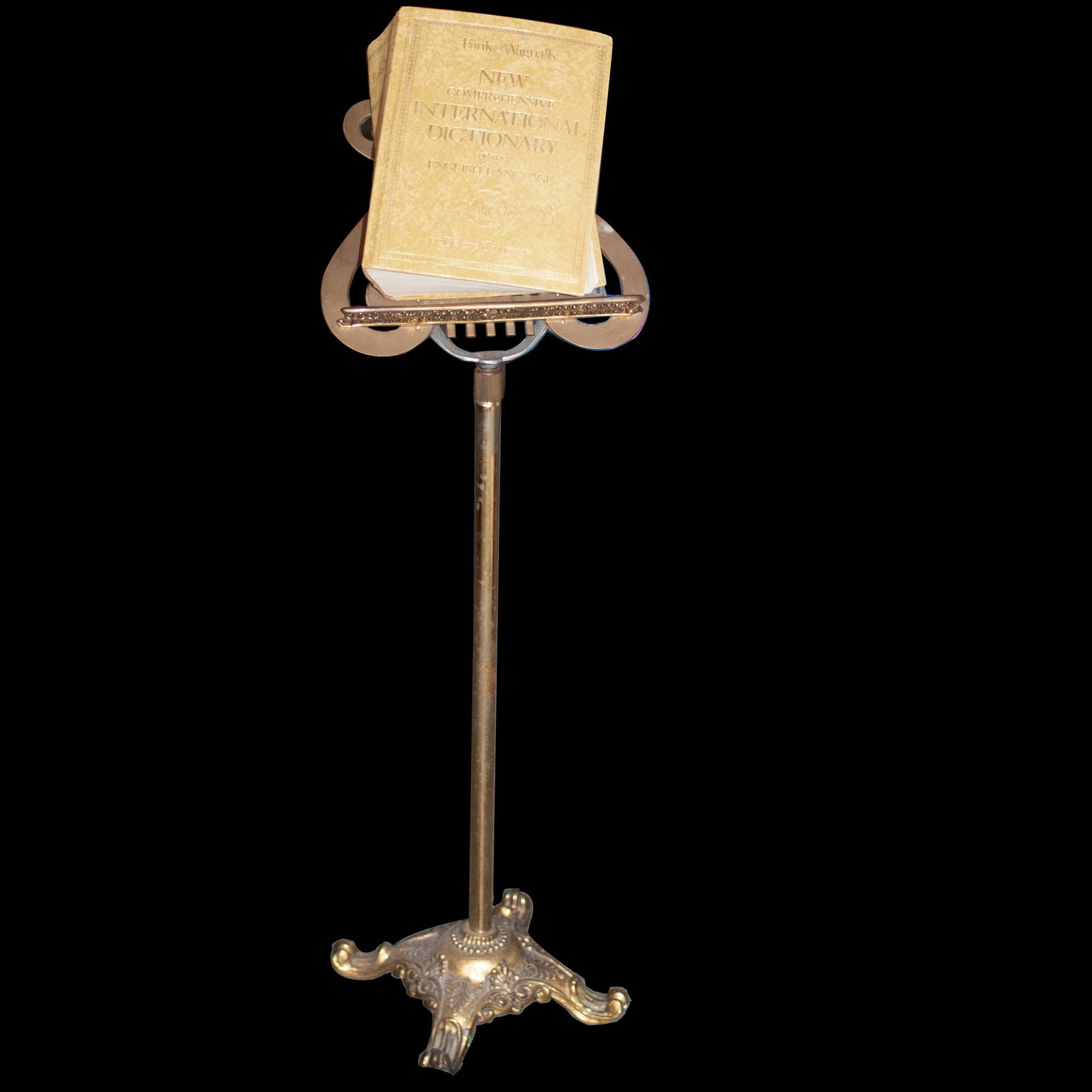 Antique Brass Music Stand: DESCRIPTION: An antique music stand composed of an overall brass foundation with a scrolled Rococo floral motif base supported by four scrolled feet. The base is centered by a rod, topped with a lyre