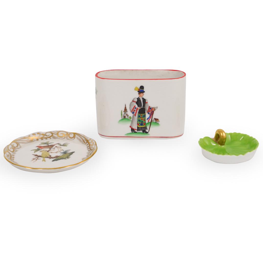 (3 Pc) Herend Porcelain Table Articles: DESCRIPTION: A lot of three Herend porcelain hand painted table articles, including a tooth pick holder with hungarian man depicted on the front, a miniature lily pad tray in green, and a hand painted
