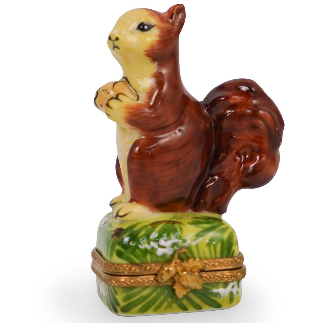 Limoges Porcelain Squirrel Trinket Box: DESCRIPTION: A porcelain limoges box decorated along the lid with a squirrel holding an acorn. Finished with brass lining along the enclosure and marked along the underside "Limoges" CIRCA: 20th Centu