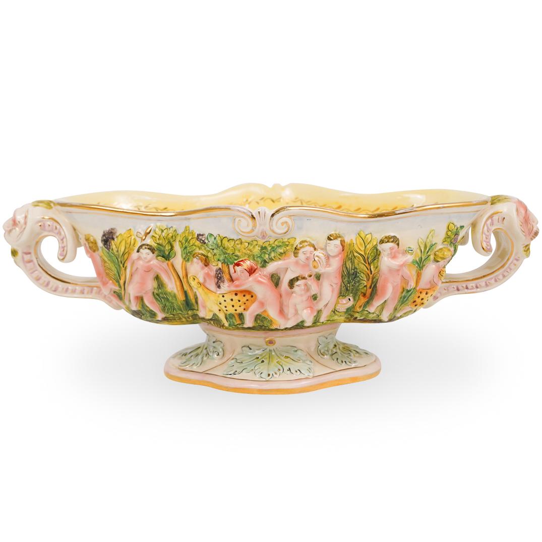 Capodimonte Porcelain Center Bowl: DESCRIPTION: A Large capodimonte porcelain center bowl decorated along the sides of the bowl with nude figures and animals, further flanked on either side by satyr heads. Finished with glaze over and