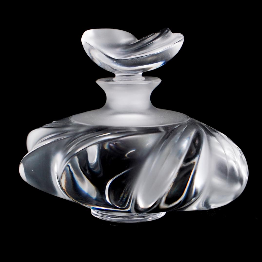 Lalique Perfume Bottle: DESCRIPTION: A Lalique perfume bottle, featuring a floral motif topper and symmetrical body. Marked on the bottom: "Lalique France". CIRCA: 20th Century ORIGIN: France DIMENSIONS: H: 3.5" W:4" CONDITI