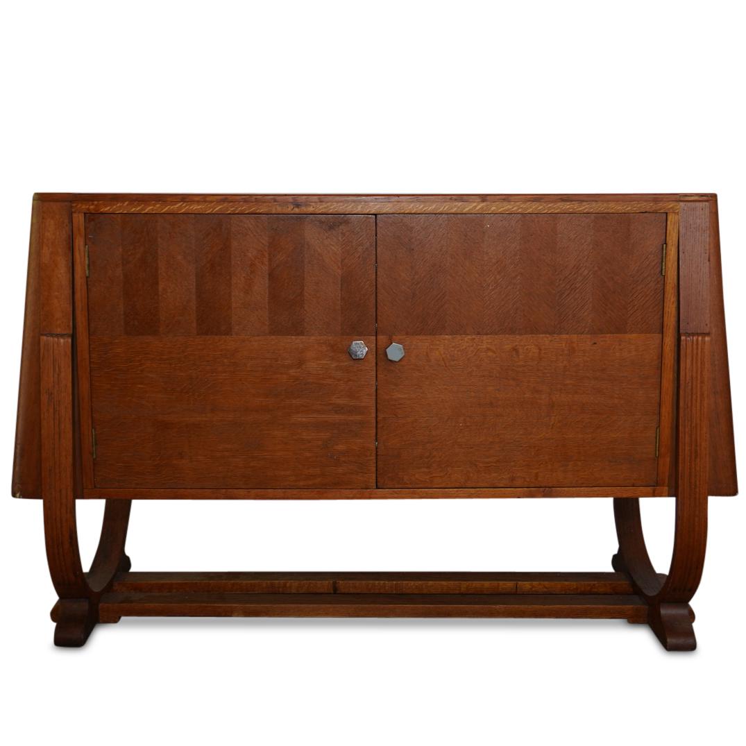 Mid Century Wood Credenza: DESCRIPTION: Mid century credenza composed of oak wood with two doors and four interior drawers. The exterior features multi patterned wood, with a unique under bridge. CIRCA: 20th Ct. ORIGIN: Denmark