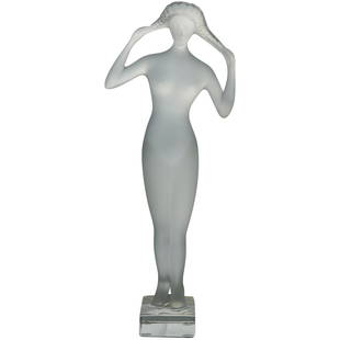 Tall Lalique Crystal "Isis Muse" Figurine: A tall Lalique crystal "Isis Muse" figurine featuring Muse in a frosted crystal sitting on top of a clear square base playing with her hair. Traditionally marked on the base Lalique France. CIRCA: