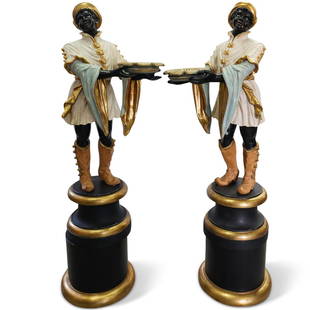 Pair Of Polychrome Blackamoor Statues: A pair of Italian polychrome blackamoor statues composed of hand carved giltwood, wearing white coats and gold boots, holding serving trays. Displayed on round black painted, gold leaf accented