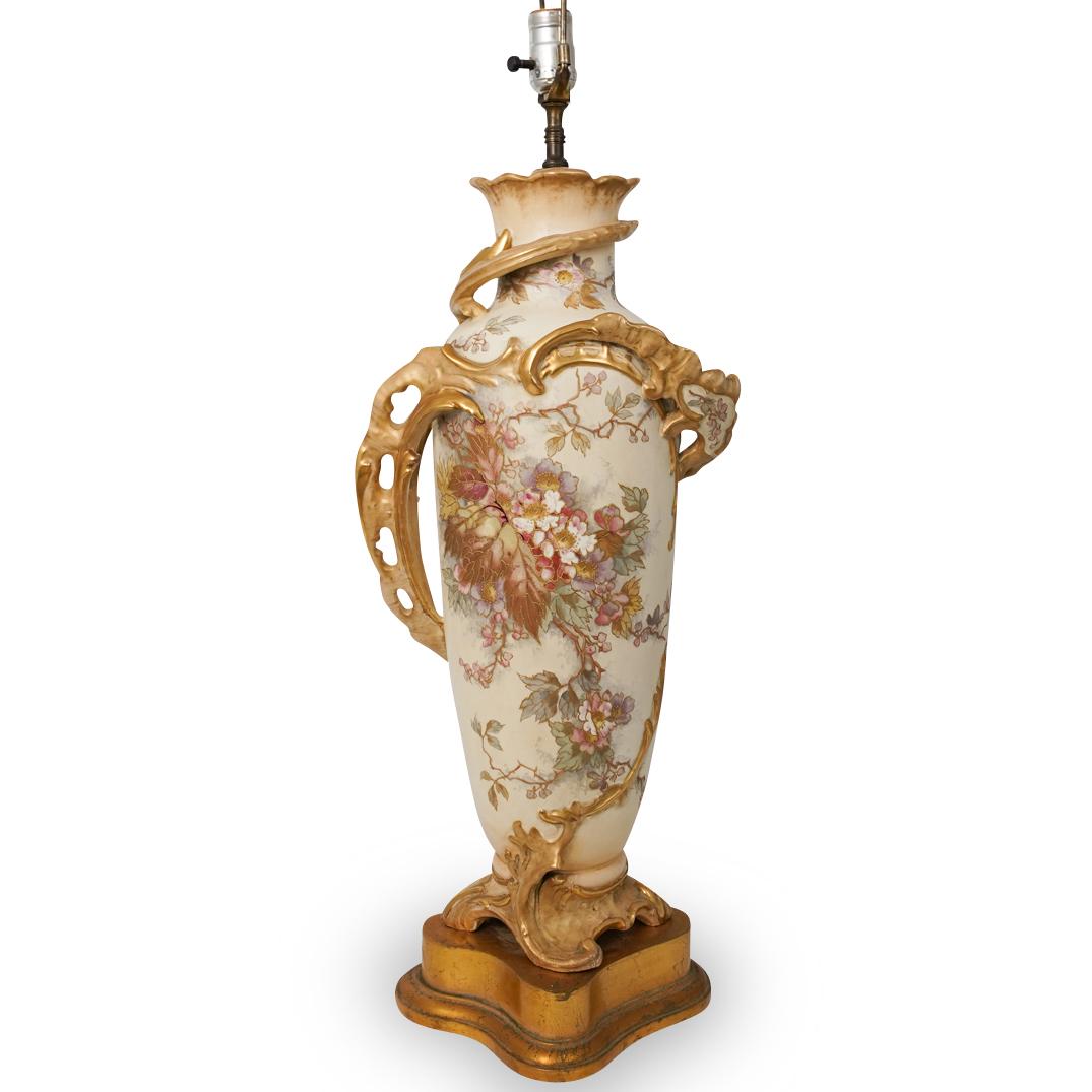Antique Royal Bonn Porcelain Lamp: Antique Royal Bonn Porcelain Lamp. Features an overall Art Nouveau motif with embellishment of pink and light blue hued flowers lined with gilded trims and gilded leaves. The top is embellished with e