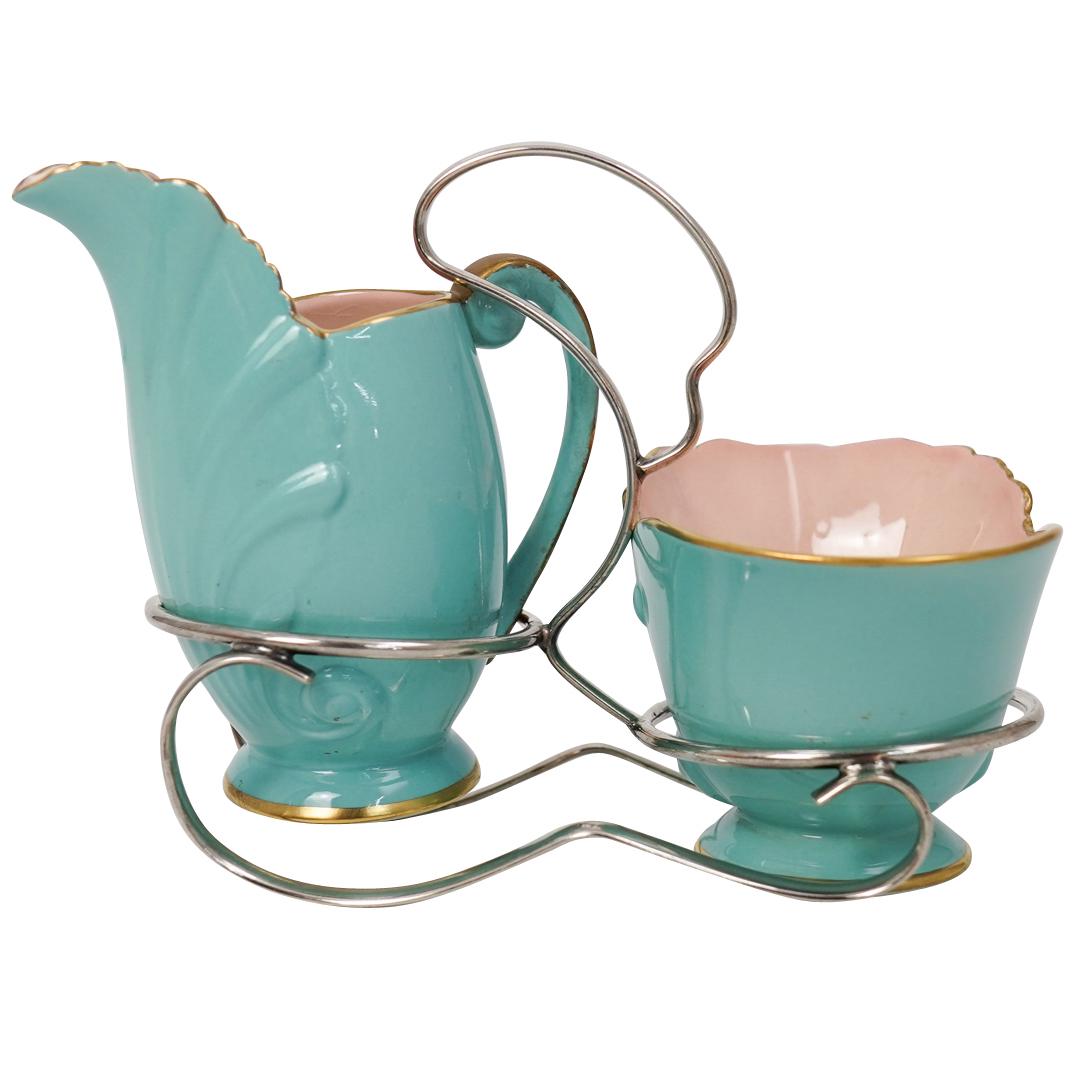 Carlton Ware Porcelain Set: Carlton Ware Porcelain Set. Features an overall teal color with pink interior and gilded trim. Traditionally marked on the bottom. Comes with a silver plated stand. Composed of a creamer and sugar hol