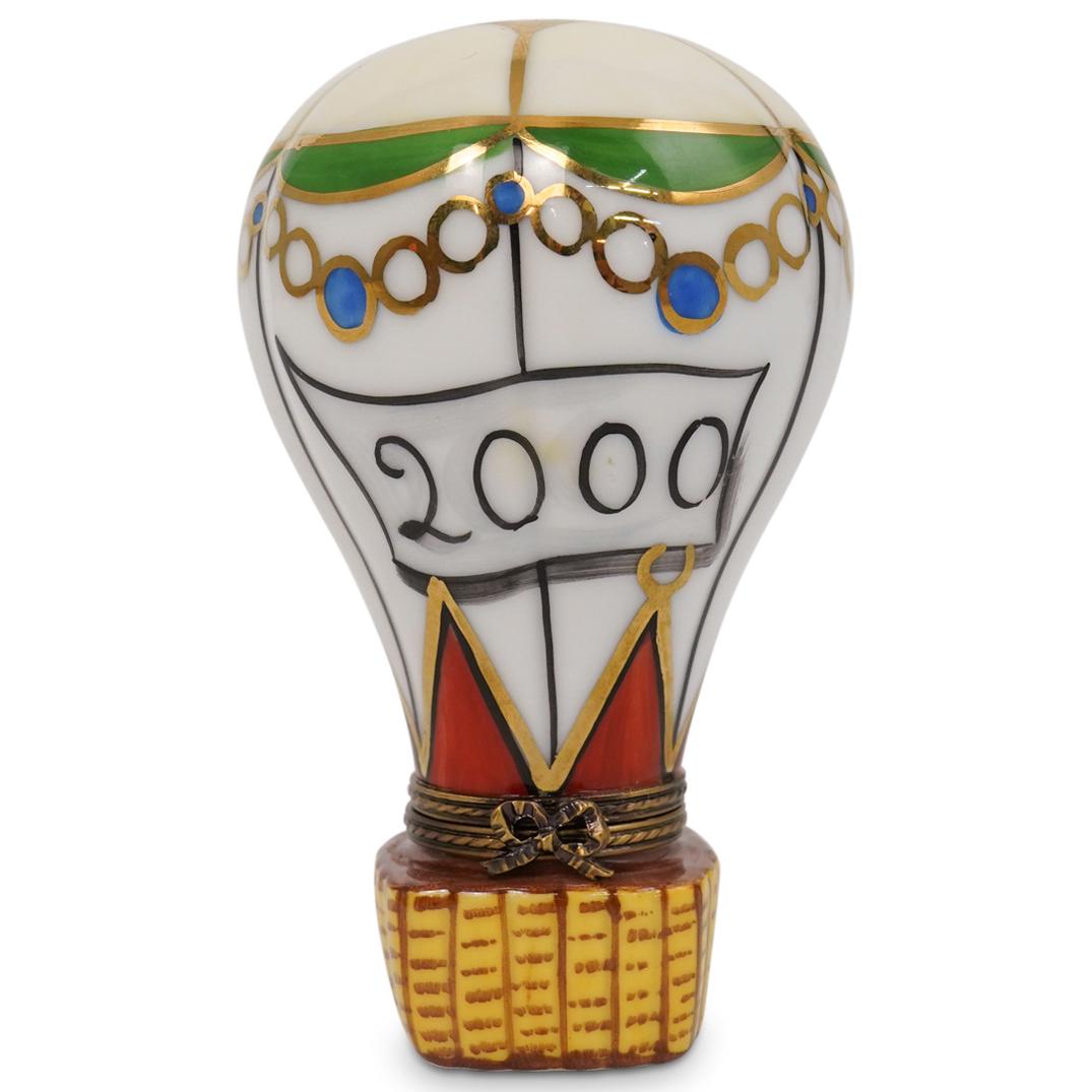 Limoges Hot Air Balloon Pill Box: A Limoges hand painted porcelain trinket box in the shape of a hot air balloon, finished with gilded ribbon form clasp. Marked on the underside: "Peint Main Limoges France La Gloriette" CIRCA: 20th Ce