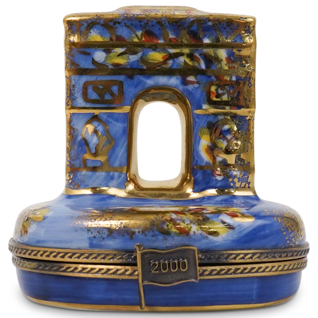 Limoges 2000 Pill Box: Limoges pill box featuring an arch with blue hues and gold accents. Clasp in the motif of a flag marked "2000" "Peint Main Limoges France La Gloriette." CIRCA: 20th Ct. ORIGIN: France DIMENSIONS: H: 2