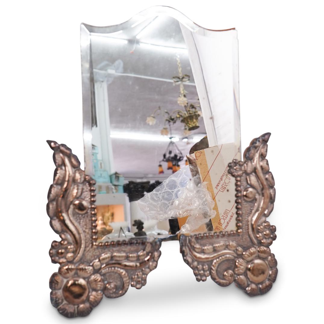Sterling Silver Mirror: Sterling silver mirror with exposed glass on the top half, while the bottom half has sterling silver trimming with floral motif. Marked "Peru" "925" CIRCA: 20th Century ORIGIN: Peru DIMENSIONS: L 19.0