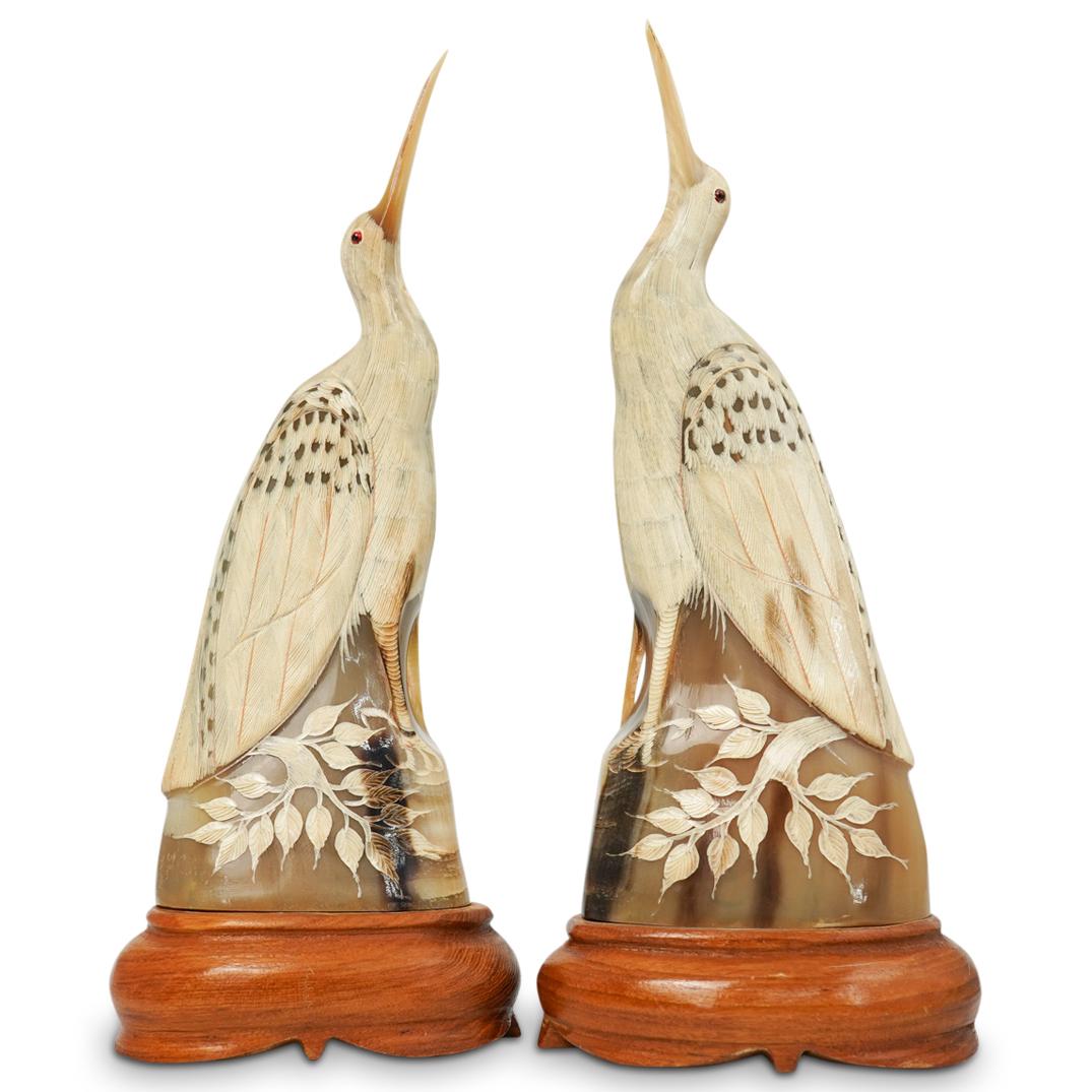 Pair Of Horn Carved Figural Birds: DESCRIPTION: A pair of figural birds composed of hand carved buffalo horn with intricately detailed feathers, glass inlaid eyes, and tree branch motif design at base. Rests on carved wood bases.CIRCA: