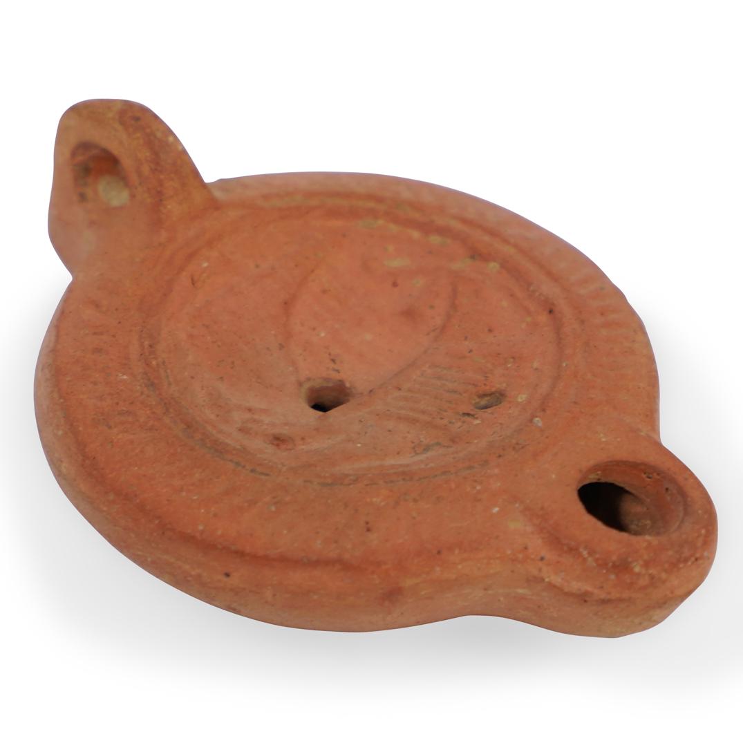Ancient Roman Terracotta Oil Lamp: DESCRIPTION: An Ancient Roman Terracotta Oil Lamp features a volute nozzle with the central discus moulded with sail and oars, completed by a loop handle. Comes with COA from ArtemissionCIRCA: 2nd-3rd