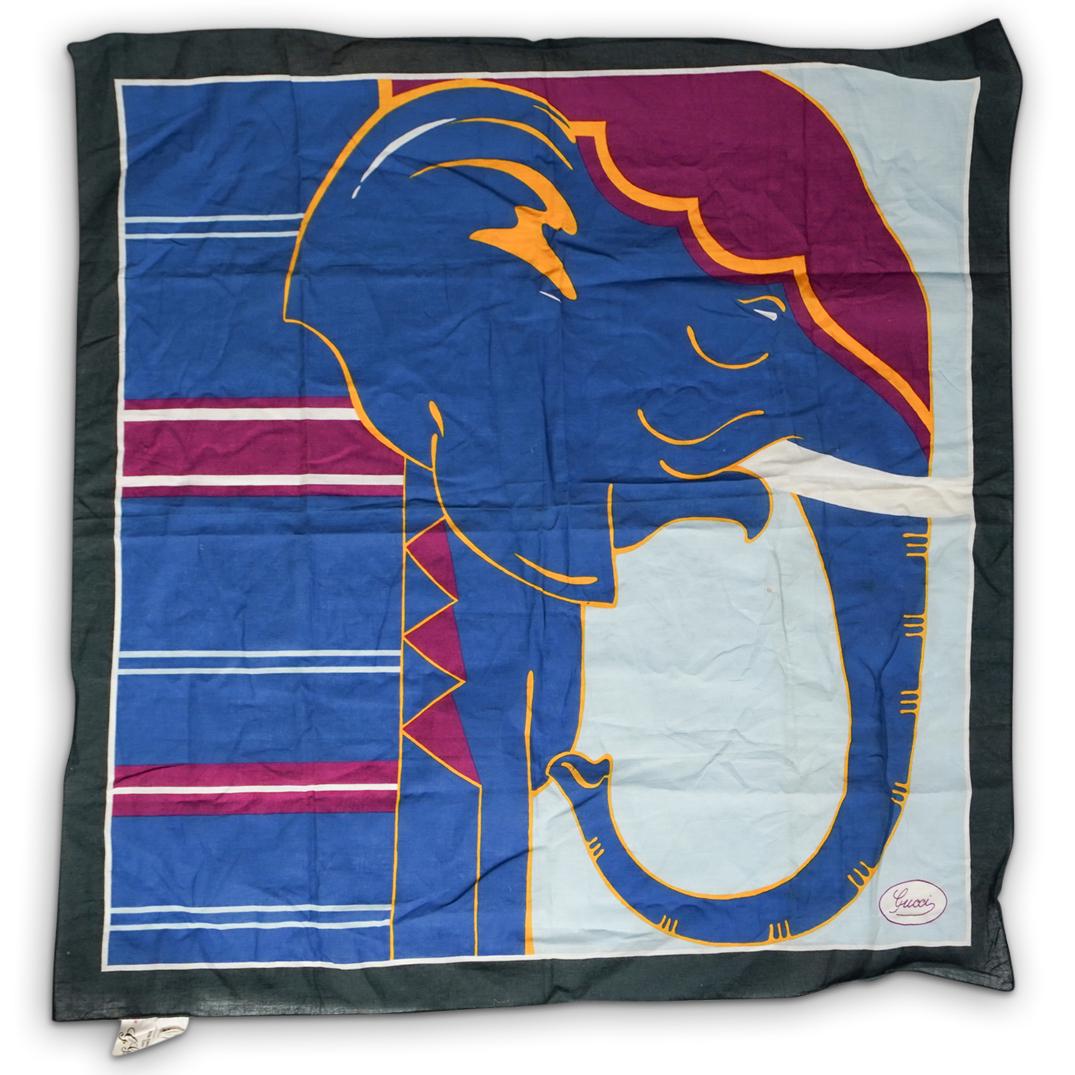 G. Gucci Elephant Bandana: DESCRIPTION: A G. Gucci bandana depicting an elephant in blue, pink, and yellow color tones. Marked "Gucci" lower right corner. Tag attached "G.Gucci s.p.a. Made In Italy" CIRCA: 20th Ct. ORIGIN: Ital