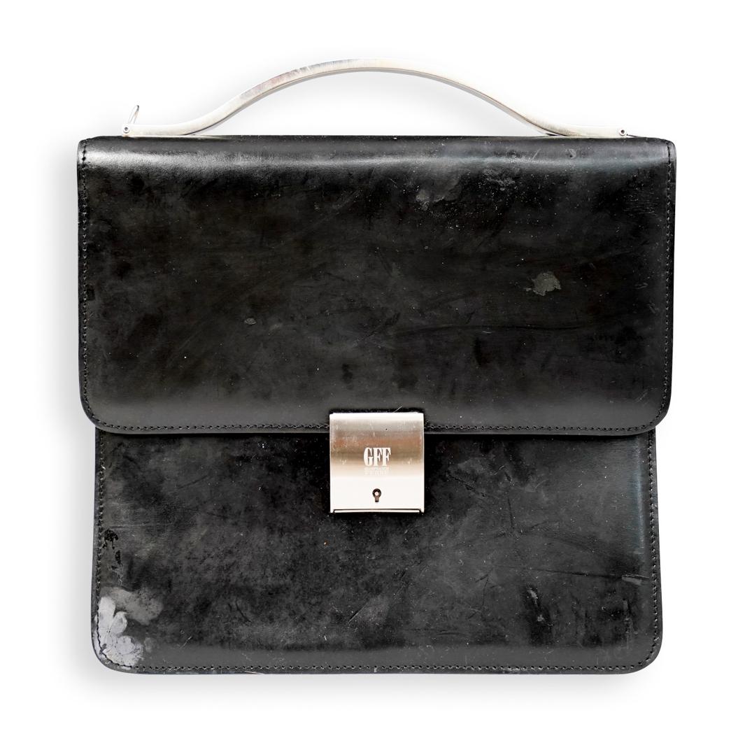 Gianfranco Ferre Black Leather Ladies Briefcase: DESCRIPTION: A Gianfranco Ferre black leather ladies briefcase. Features silver-toned hardware handle, flap opening mounted with key locking hardware. Interior lined with black fabric and side zip clo