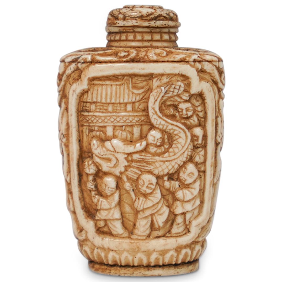 Antique Chinese Snuff Bottle: DESCRIPTION: An antique Chinese bone snuff bottle. Featuring a figural village scene on one side and a dragon parade carved motif on the other. Finished with scrolling accents and a flower adorned lid