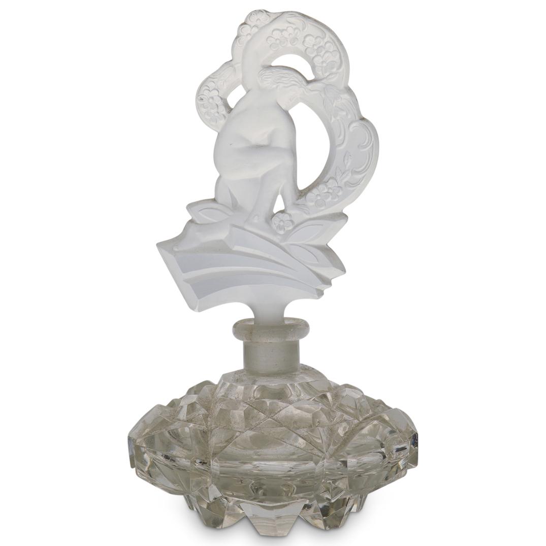 Antique Czech Perfume Bottle: DESCRIPTION: Antique Czech Perfume Bottle featuring a clear glass design with an open work stopper. The stopper depicts a nude figure surrounded by flowers. The base has a multi faceted circular desig