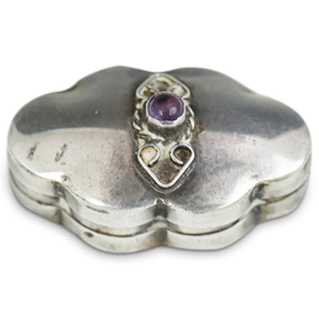 Sterling Silver Pill Box: DESCRIPTION: Sterling silver pill box adorned with Amethyst stone at the center of the lid. Marked "sterling" Total Weight: CIRCA: 20th Century ORIGIN: USA DIMENSIONS: L 0.5" x W 1.0" CONDITION: Great