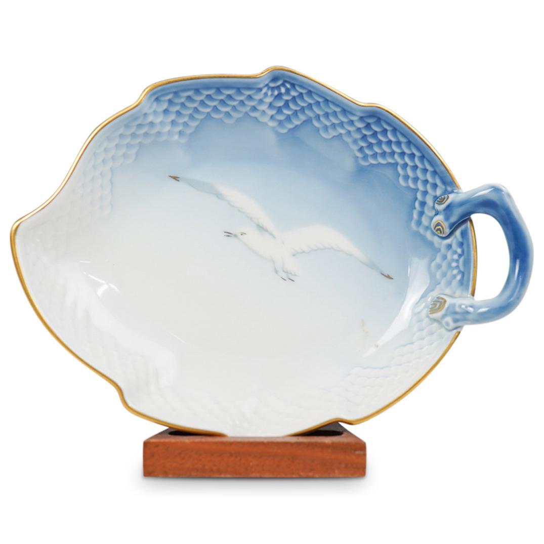Bing & Grondahl Porcelain Dish: DESCRIPTION: Bing & Grondahl Porcelain Dish. Features an overall blue an white color, with depictions of a seagull. Finished with a leaf design and one handle. Traditionally marked on the bottom "B&G"