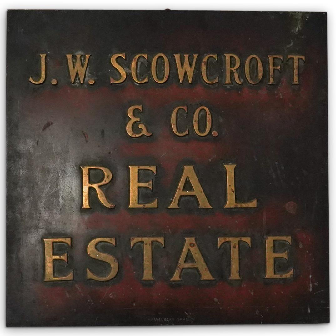 Vintage J.W Scowcroft and Co. Real Estate Sign: DESCRIPTION: A Vintage Brass over wood sign for company J.W Scowcroft and Co. Real estate, completed with gilt lettering. Has oxidized patina. CIRCA: Mid 20th Cent. ORIGIN: USA DIMENSIONS: 23.5" x 22"