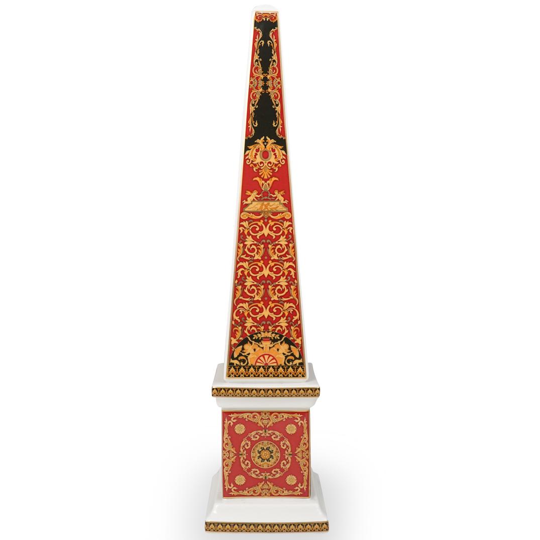 Versace Rosenthal "Medusa" Obelisk: DESCRIPTION: Versace Rosenthal "Medusa" Obelisk decorated in red and black tones, accented by gilt ornate trims and Medusa heads. Marked along the underside. CIRCA: 20th Century ORIGIN: France DIMENSI