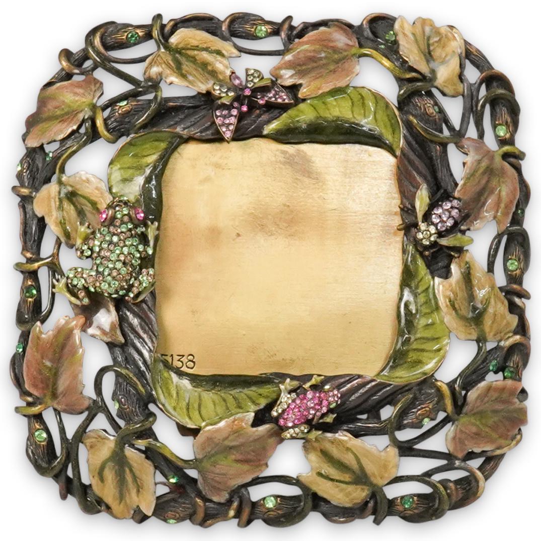 Jay Strongwater Frame: DESCRIPTION: A Jay Strongwater picture frame. Features pink green crystals encompassing the square frame with a multi colored floral enamel border and an ornate reticulated stand. Marked:"Jay Strongwa