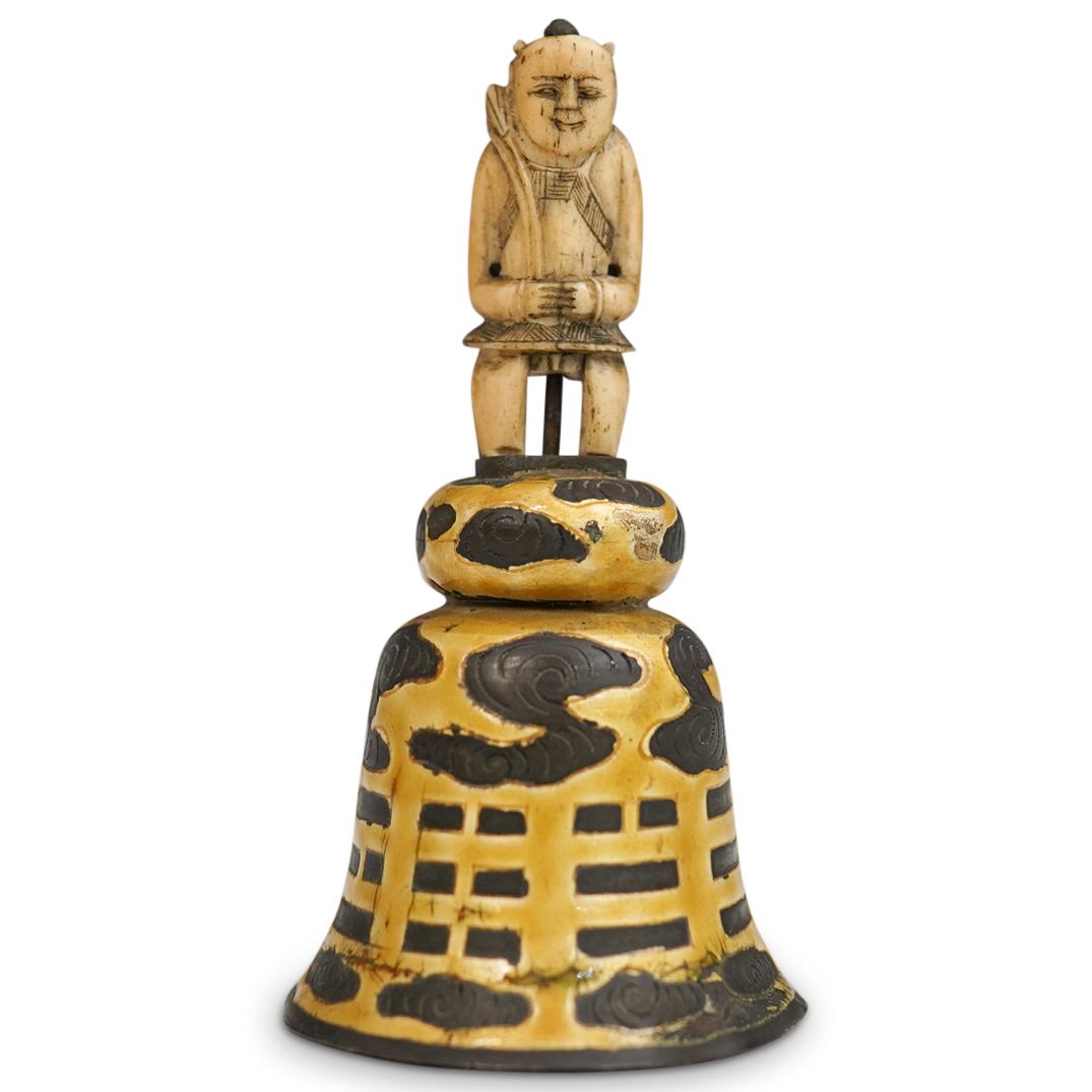 Antique Chinese Figural Bell: DESCRIPTION: An antique Chinese figural enamel bell. Features gold enameled body with dark cloud accents topped with an intricately carved bone figure. Inscribed "China" on reverse of figure. CIRCA: 1