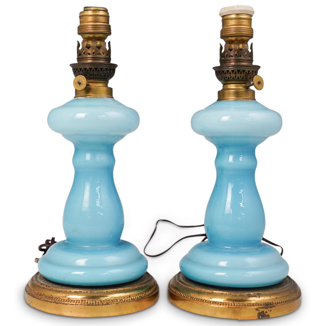 Pair Of Blue Glass Lamps: DESCRIPTION: A pair of blue glass lamps. Features two table lamps with blue toned glass bodies mounted with gilt metal bases and top converted oil lamp outlets. CIRCA: 20th Cent. ORIGIN: USA DIMENSION