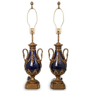 Pair of Porcelain & Dore Bronze Urn Table Lamps: DESCRIPTION: A pair of cobalt blue porcelain urns that have been converted into electric lamps. Features dore bronze swan handles and floral wreaths tied together by a bow that string along the