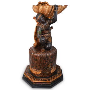 Antique Wooden Blackamoor Pedestal: DESCRIPTION: Antique wooden polychrome blackamoor pedestal featuring a kneeling figure on a pedestal holding a large shell on his shoulder. Figure is dressed in highly decorated traditional print