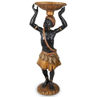 Antique Polychrome Blackamoor Pedestal: DESCRIPTION: Antique Polychrome Blackamoor Pedestal composed of hand carved wood, depicting a male figure wearing traditional clothing and holding a serving tray. Displayed on round gilded base.