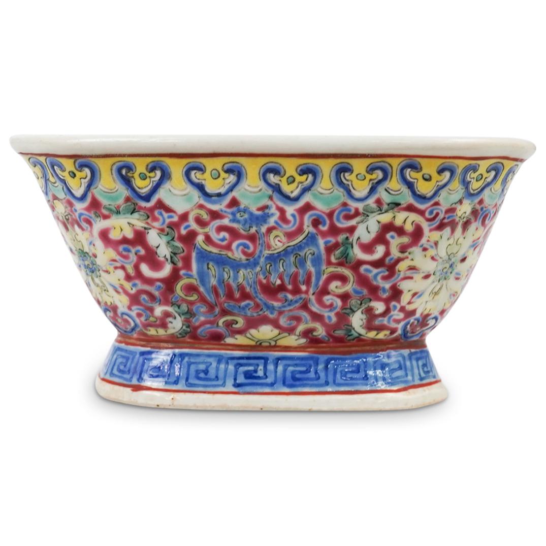 Chinese Porcelain Footed Bowl: DESCRIPTION: A Chinese porcelain bowl with raised multi colored ground enameled designs. Features floral and phoenix decorations with meandering bordering. Red character stamp underneath. CIRCA: 20th 
