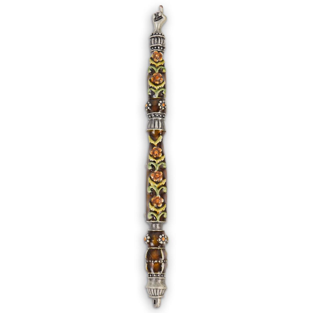 Enameled Torah Pointer: DESCRIPTION: A "Jay Strongwater" style red enameled Torah pointer with hand motif tip and crystal set floral decorations. CIRCA: 20th Cent. ORIGIN: Israel DIMENSIONS: L: 6.25" CONDITION: Great conditi