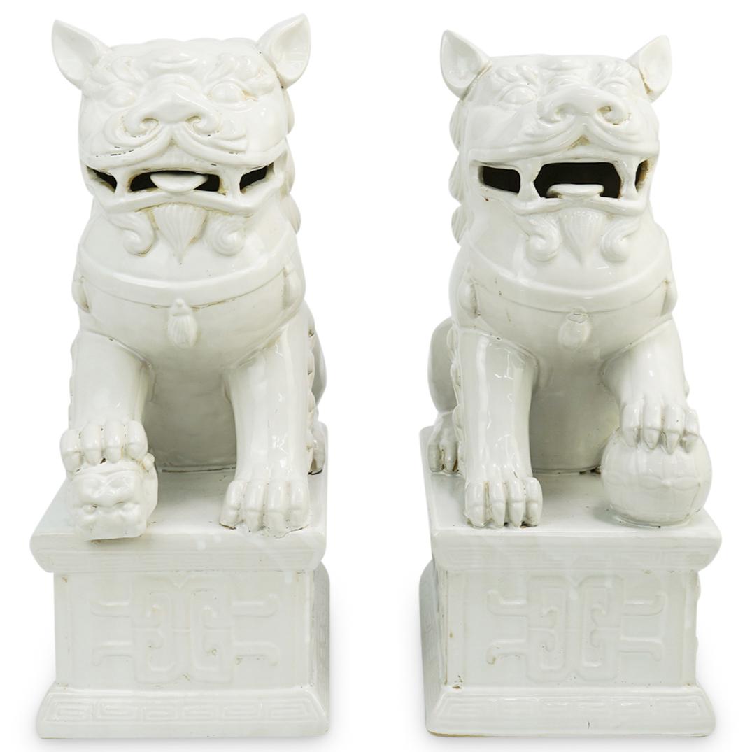 Pair of White Porcelain Foo Dogs: DESCRIPTION: Pair of white chinoiserie glazed porcelain foo dogs resting on a base with geometrical chinese motifs. The male dog holds a globe under his right paw showing domain over the home. The fem