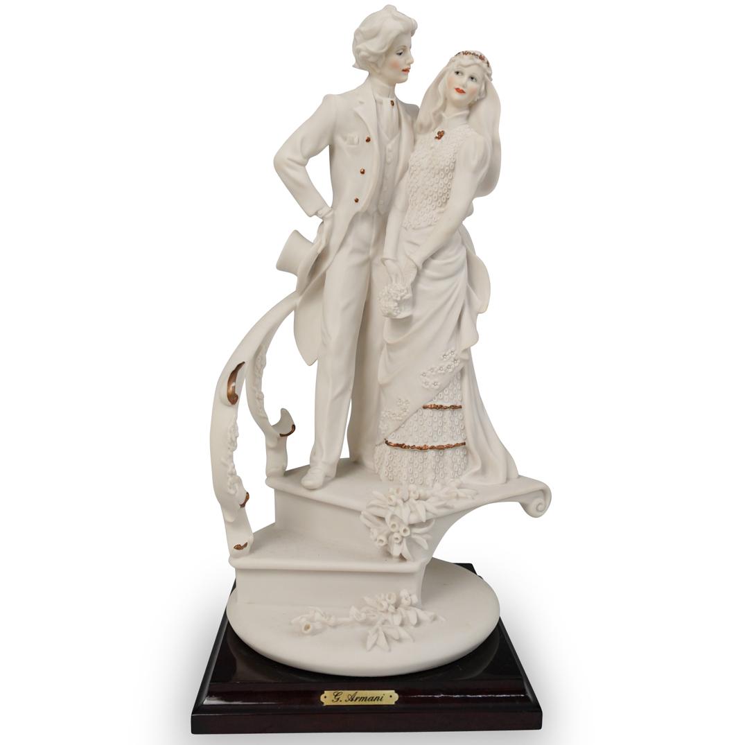 Giuseppe Armani "Bride and Groom" Porcelain Statue: DESCRIPTION: Giuseppe Armani "Bride and Groom" #1611. Depicts a groom embracing his bride while standing on a staircase. The figurine features a matte finish and is mounted on a mahogany wood base. Si