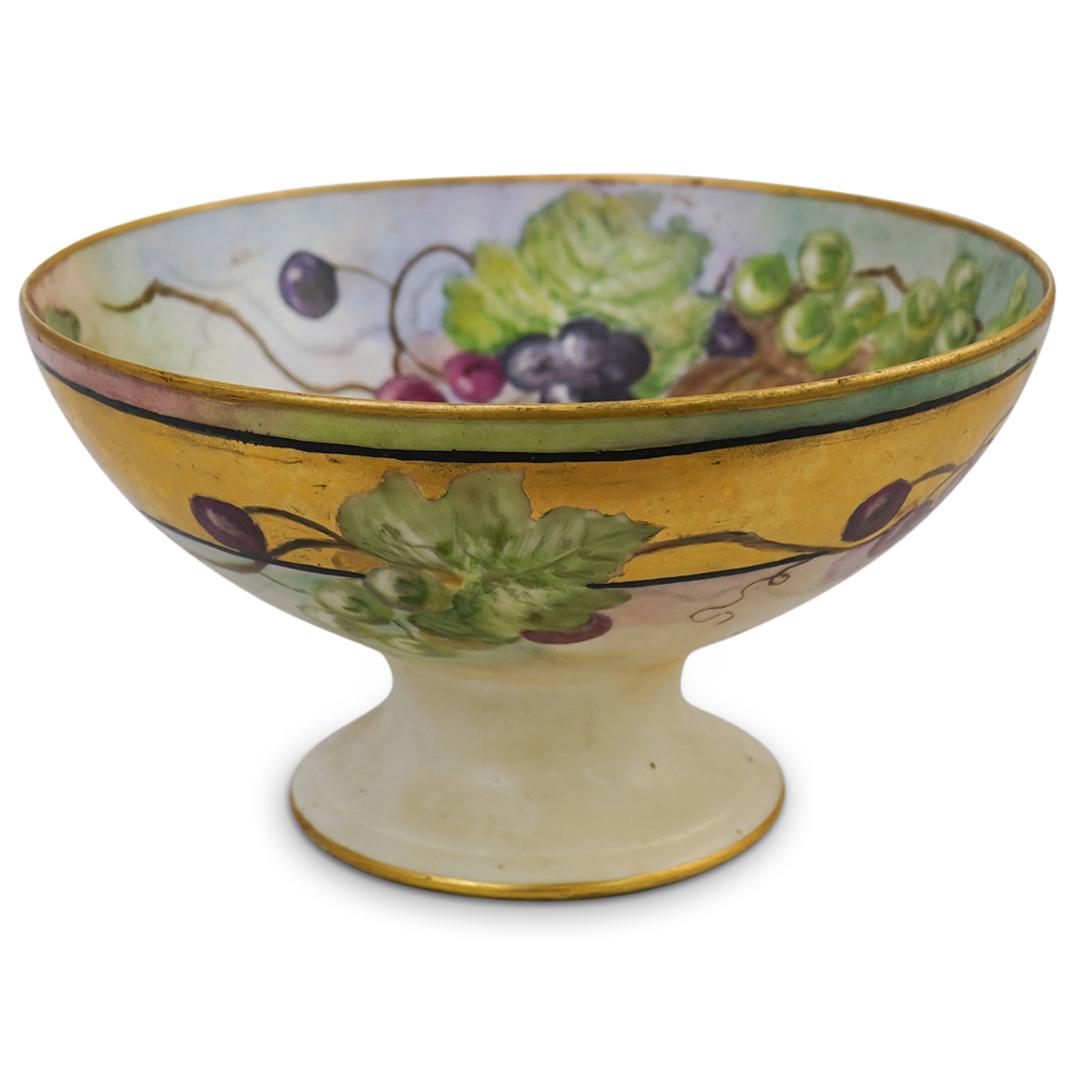 Signed Porcelain Fruit Centerpiece Bowl: DESCRIPTION: Porcelain round fruit centerpiece pedestal bowl. Hand-painted pattern by artist G. Johnson with decorations of juicy clusters of purple red and green grapes and grapevine plant leaves aga