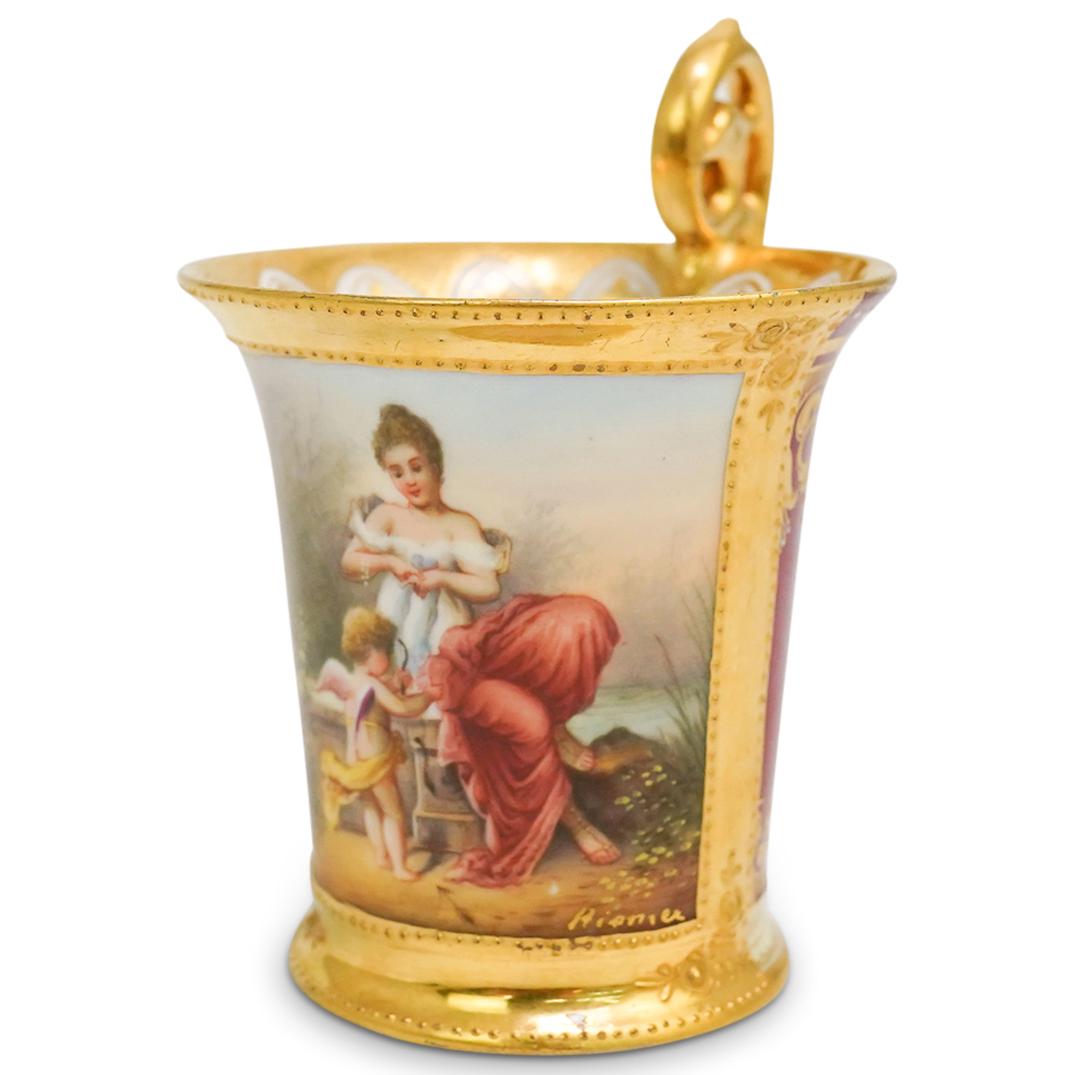 Royal Vienna Porcelain Tea Cup: DESCRIPTION: An Royal Vienna porcelain tea cup with figural scenes and gilt accented designs, signed "Hienie's" below image and "Geschieht Dir recht" with beehive mark underneath. CIRCA: 20th Cent. OR