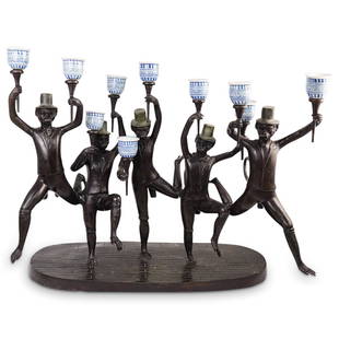 Maitland Smith Dancing Monkey Candelabra: DESCRIPTION: A "Maitland Smith" candelabra composed of cast metal depicting five suit adorned monkeys supporting blue and white ceramic candle holders. Maitland Smith label attached underneath.