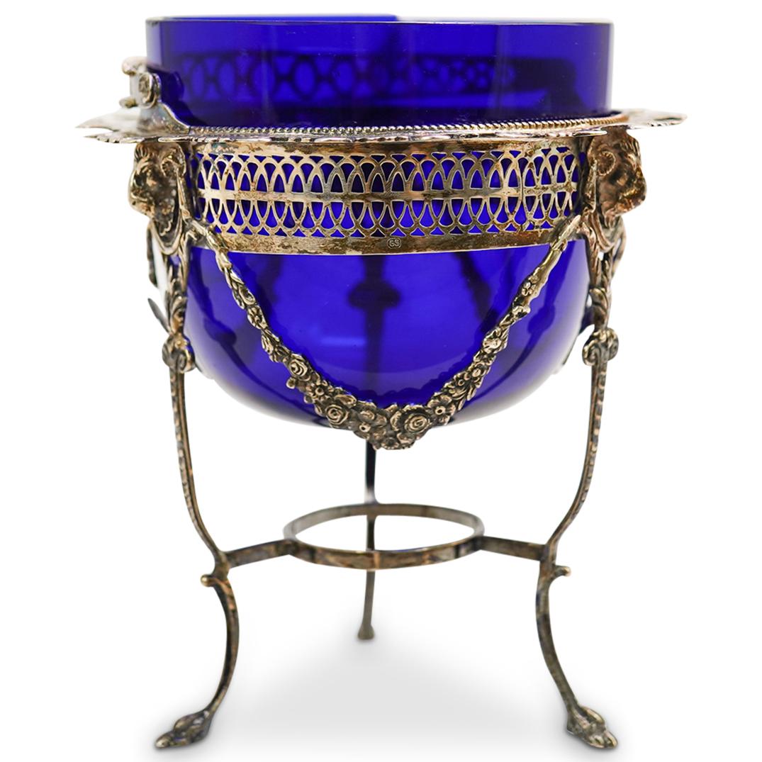 English Sterling Silver and Cobalt Blue Glass Caddy: DESCRIPTION: A caddy composed of a sterling silver frame decorated with draping vines, animalistic feet and ram head motifs. Inserted with a cobalt blue glass bowl, stamped "T" and "GS". Total Weight 