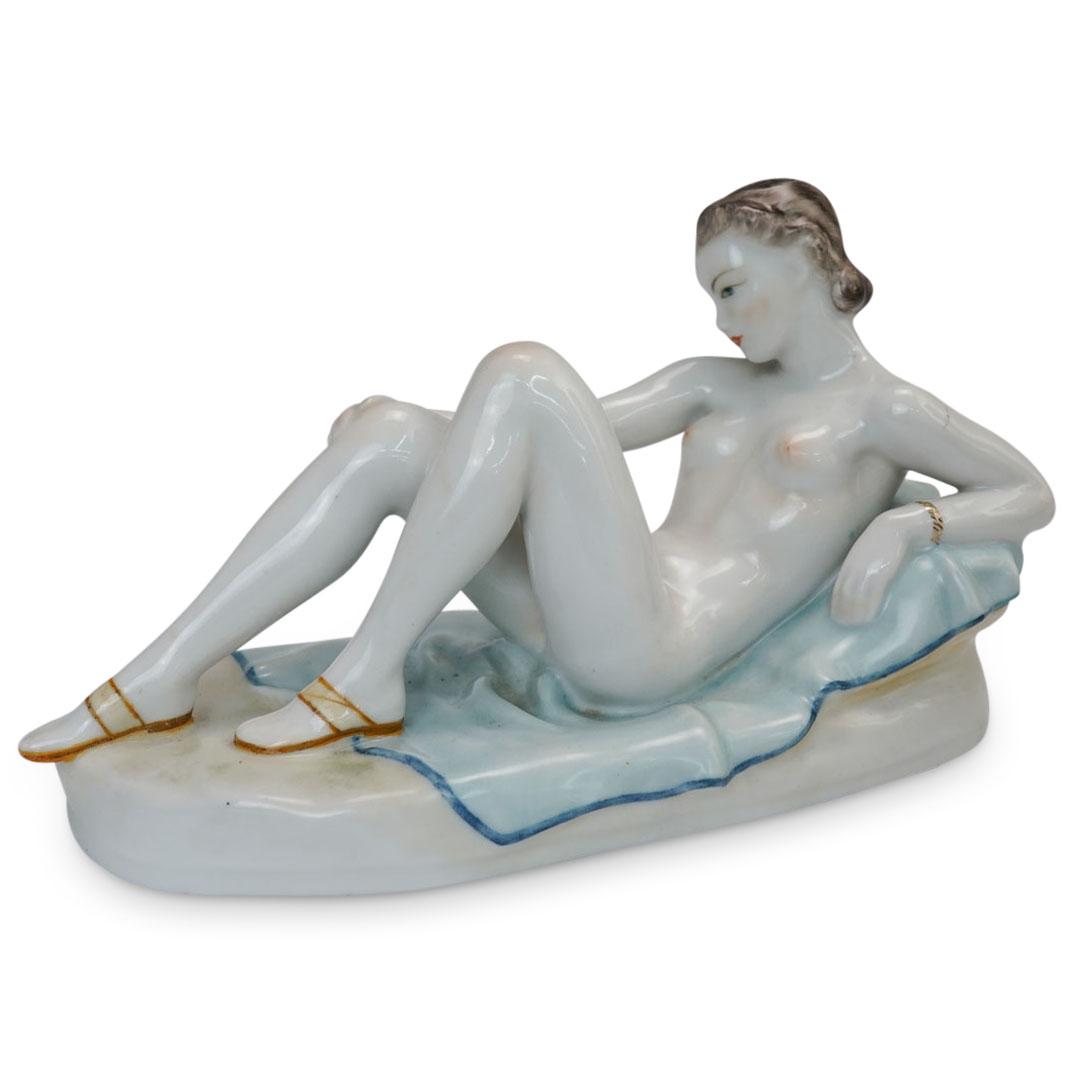 Royal Vienna Nude Porcelain Figure: DESCRIPTION: An Art Deco Royal Vienna porcelain figural statue. Features a reclined nude women on a light blue shaded blanket. Beehive marking along side.CIRCA: Early 20th Cent.ORIGIN: AustriaDIMENSIO